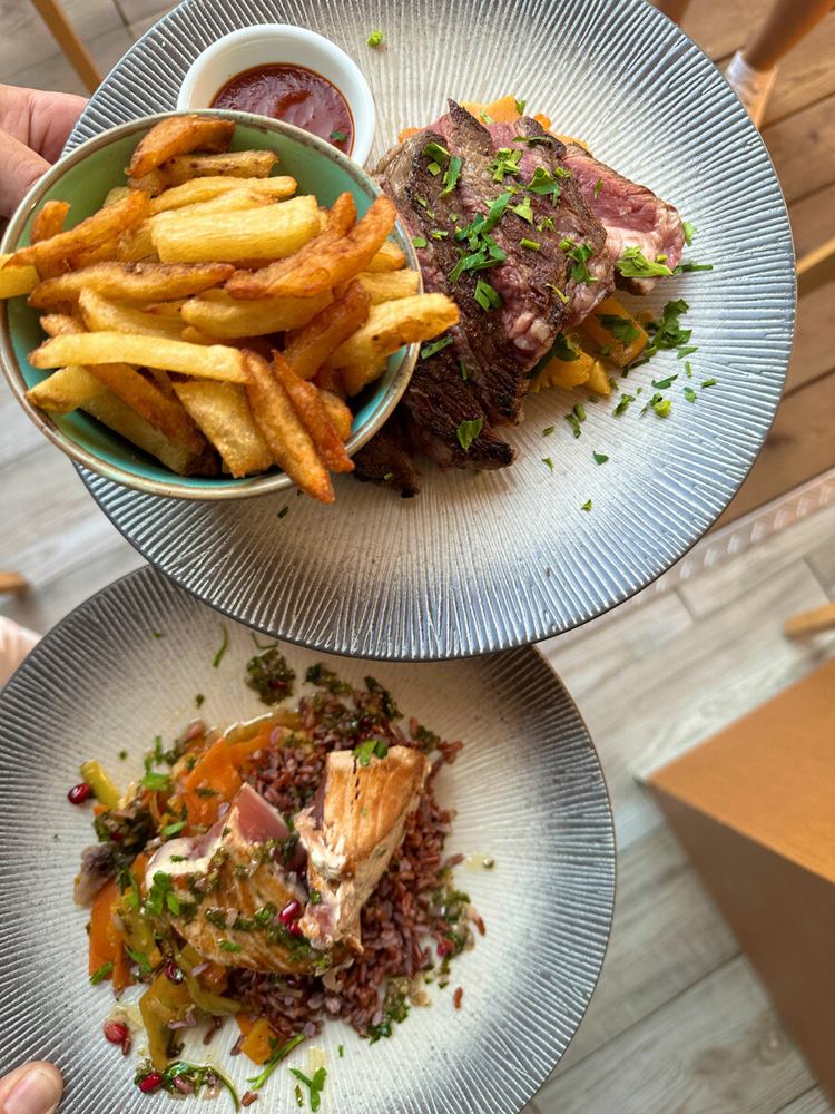 Photo du restaurant : un steak frites et une assiette de poisson dressée, servis à NautiK